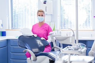 Dentist in mask looking at camera beside chair at the dental clinic.jpeg