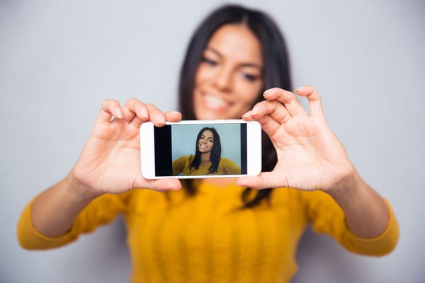 Happy woman influencer making video photo selfie on mobile. Focus on smartphone.jpeg
