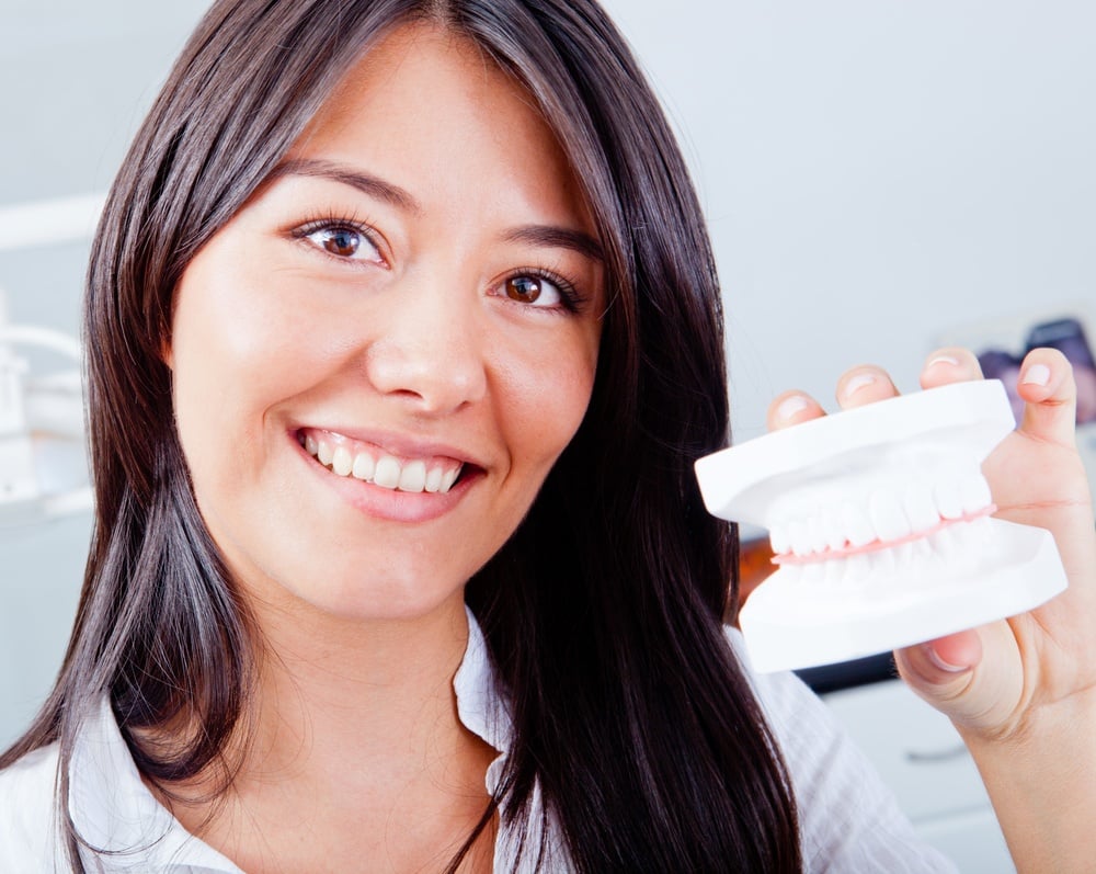 Woman holding a teeth sample or prosthesis at the dentist.jpeg